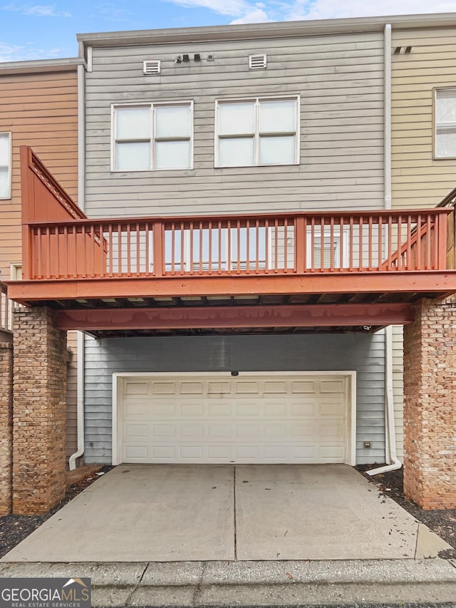 rear view of house with a garage and concrete driveway