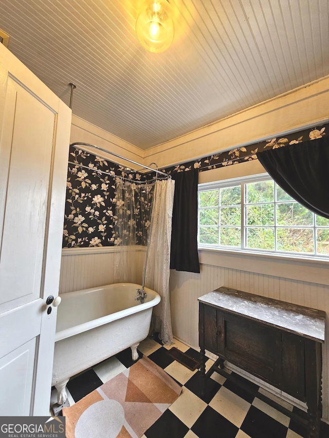 bathroom featuring a wainscoted wall, a freestanding bath, wood walls, wooden ceiling, and tile patterned floors