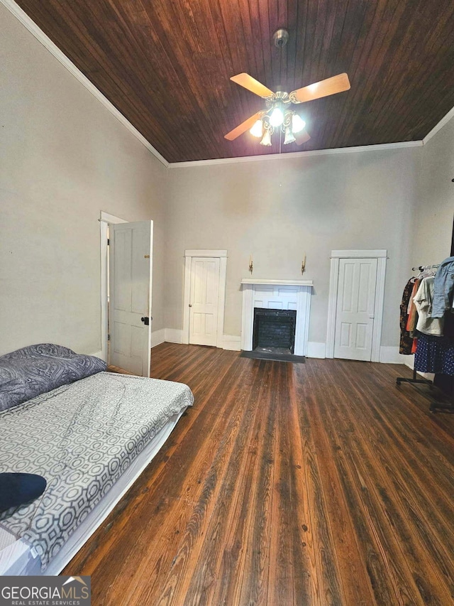 bedroom featuring a fireplace with flush hearth, crown molding, and dark wood-type flooring