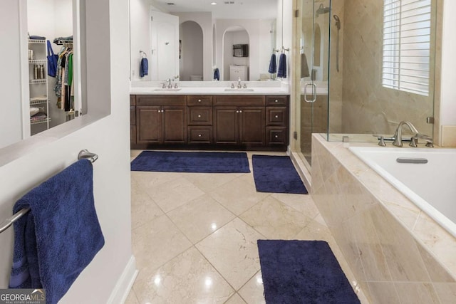 full bath with double vanity, a shower stall, a garden tub, and a sink