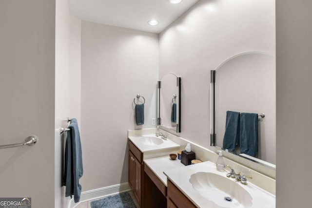 full bath with two vanities, recessed lighting, baseboards, and a sink