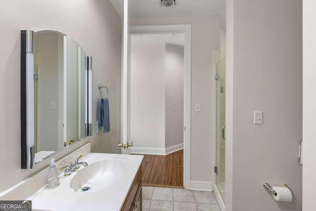 bathroom with tile patterned floors, a shower stall, vanity, and baseboards