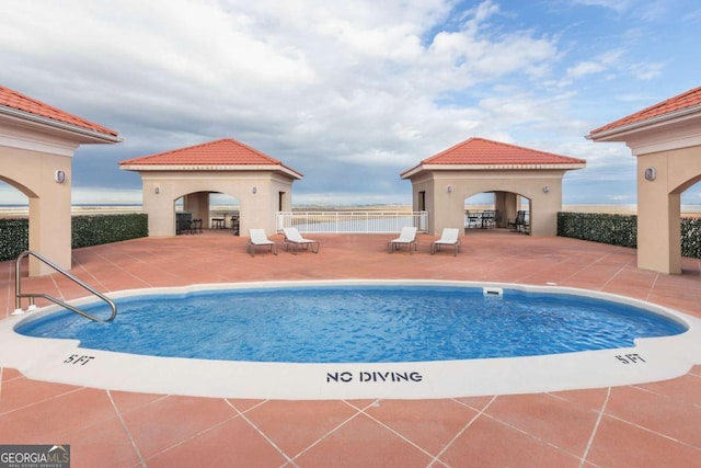 community pool with a gazebo, a patio area, and fence