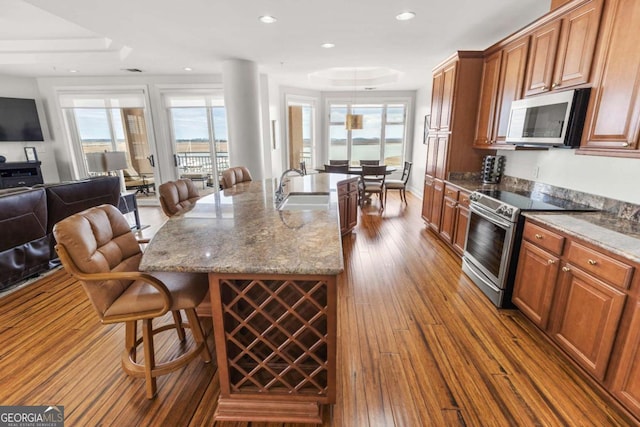 kitchen featuring dark wood-style flooring, a sink, stainless steel appliances, a kitchen breakfast bar, and open floor plan