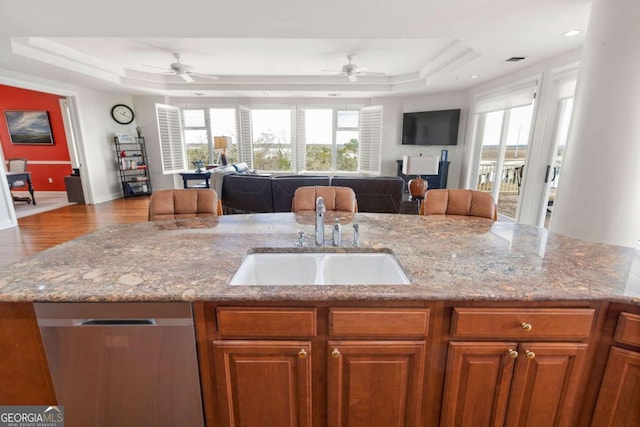 kitchen with open floor plan, a tray ceiling, and stainless steel dishwasher