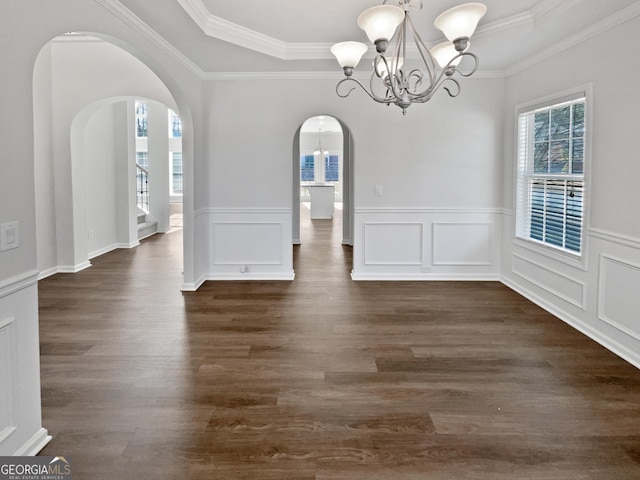 unfurnished dining area featuring arched walkways, plenty of natural light, a raised ceiling, and a notable chandelier