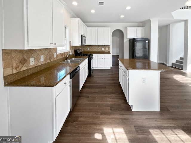 kitchen with arched walkways, a kitchen island, a sink, visible vents, and black appliances