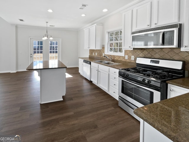 kitchen with visible vents, appliances with stainless steel finishes, dark wood-type flooring, a sink, and backsplash