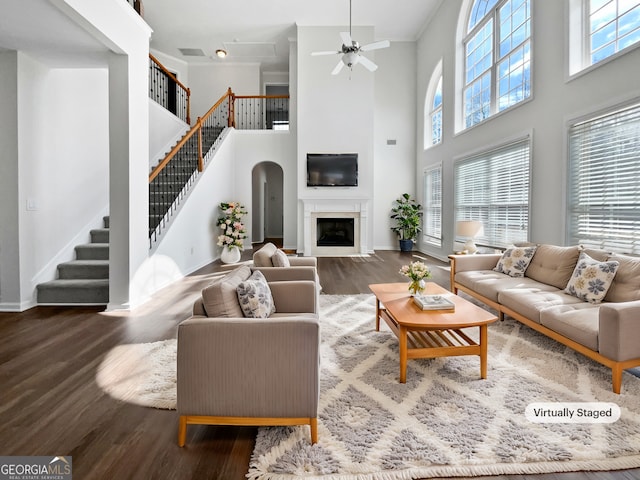 living room featuring stairway, a fireplace with flush hearth, a ceiling fan, wood finished floors, and baseboards