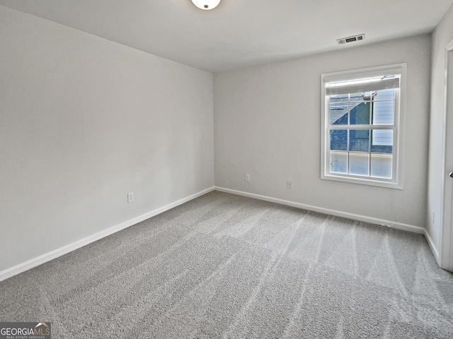 carpeted spare room featuring baseboards and visible vents