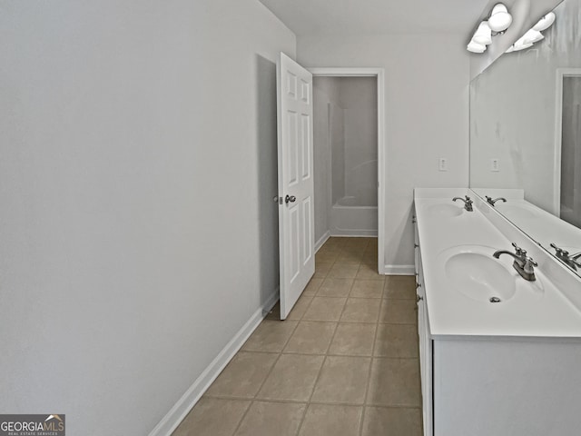 bathroom featuring double vanity, tile patterned flooring, baseboards, and a sink