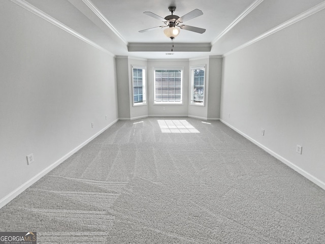 carpeted spare room with ornamental molding, a raised ceiling, ceiling fan, and baseboards