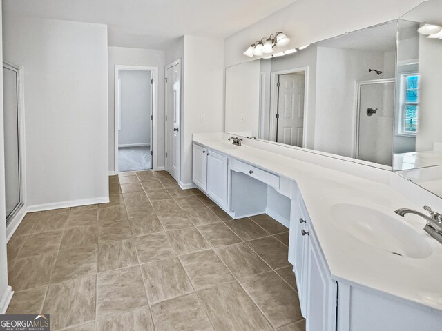 bathroom with baseboards, double vanity, a sink, and a shower stall