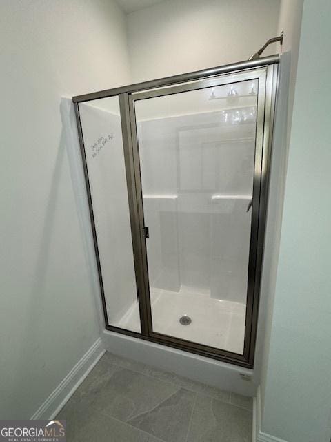bathroom featuring a shower stall and baseboards