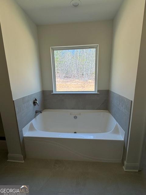 full bathroom featuring tile patterned floors and a bath