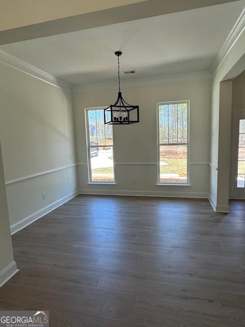unfurnished dining area with dark wood-type flooring, baseboards, ornamental molding, and visible vents