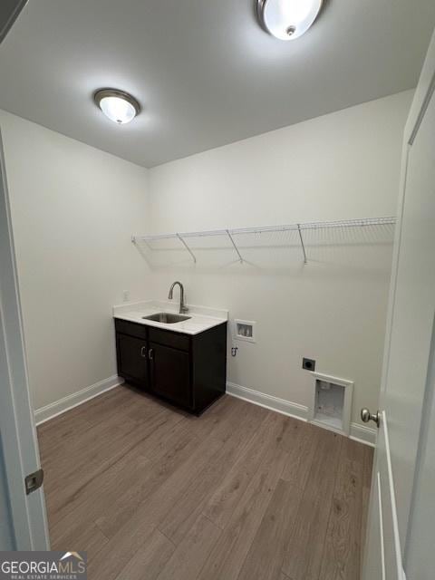 washroom with a sink, light wood-style floors, hookup for an electric dryer, cabinet space, and hookup for a washing machine
