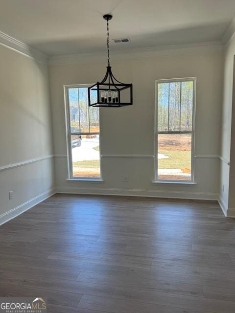 unfurnished dining area with a chandelier, crown molding, and dark wood finished floors