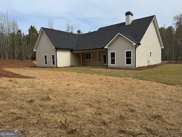back of property with a patio area, a shingled roof, and a chimney