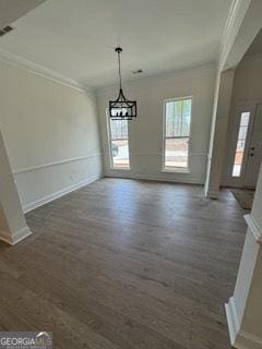 unfurnished dining area with visible vents, baseboards, ornamental molding, a chandelier, and dark wood-style floors
