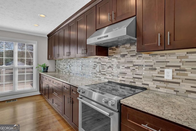 kitchen with light stone counters, electric stove, visible vents, and wall chimney exhaust hood