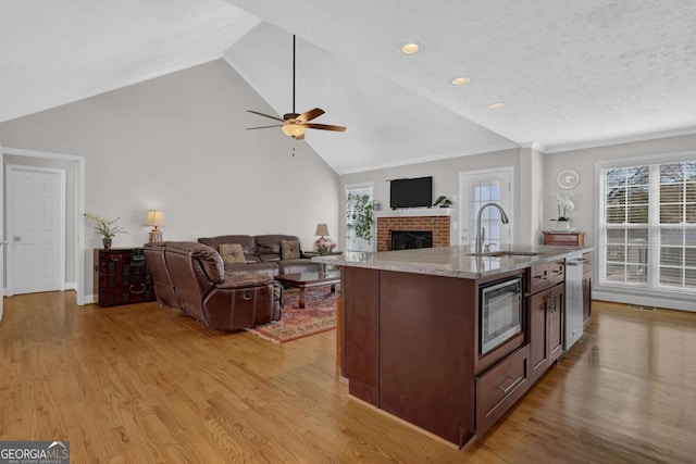 kitchen with an island with sink, stainless steel appliances, open floor plan, and a sink