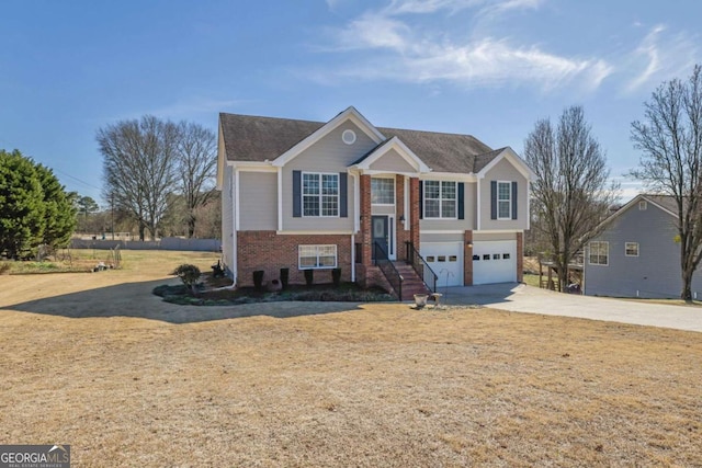 bi-level home featuring a garage, brick siding, and driveway