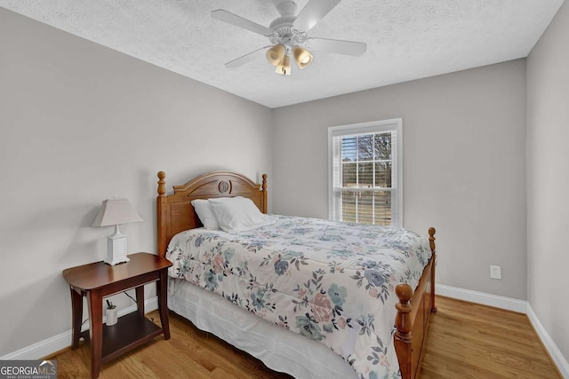 bedroom featuring a textured ceiling, ceiling fan, wood finished floors, and baseboards