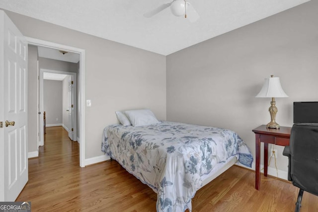 bedroom with a ceiling fan, baseboards, and wood finished floors