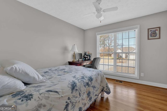 bedroom featuring visible vents, ceiling fan, a textured ceiling, wood finished floors, and baseboards