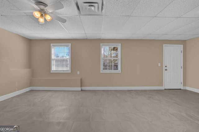 unfurnished room featuring a ceiling fan, a drop ceiling, visible vents, and baseboards