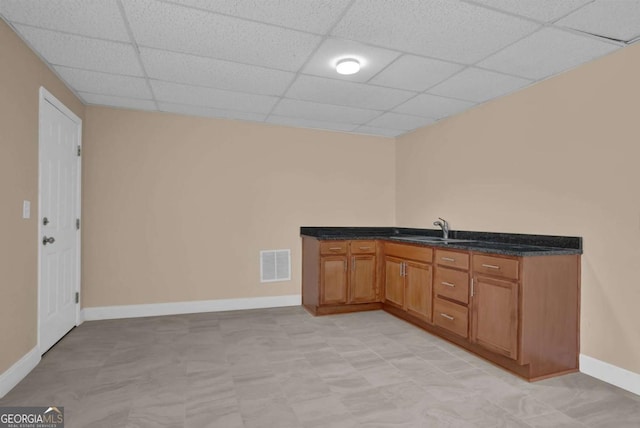 bar featuring a paneled ceiling, a sink, visible vents, and baseboards