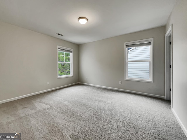 carpeted spare room featuring visible vents and baseboards