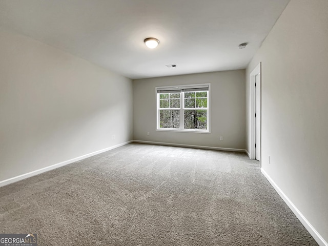 unfurnished room with carpet flooring, visible vents, and baseboards