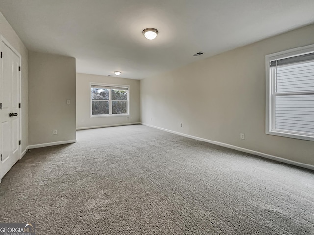 carpeted spare room featuring visible vents and baseboards