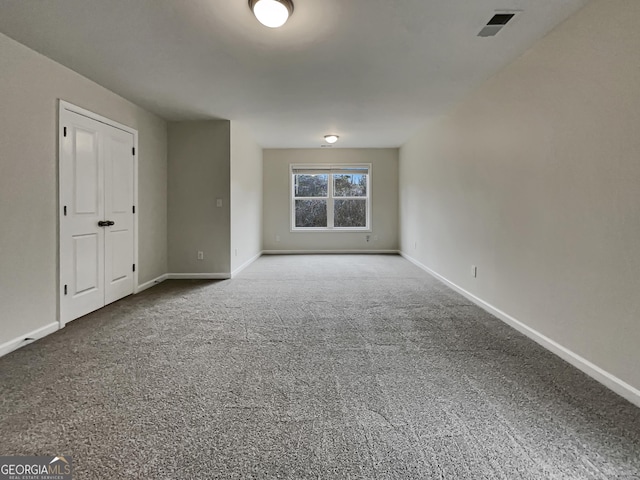 spare room with carpet floors, visible vents, and baseboards