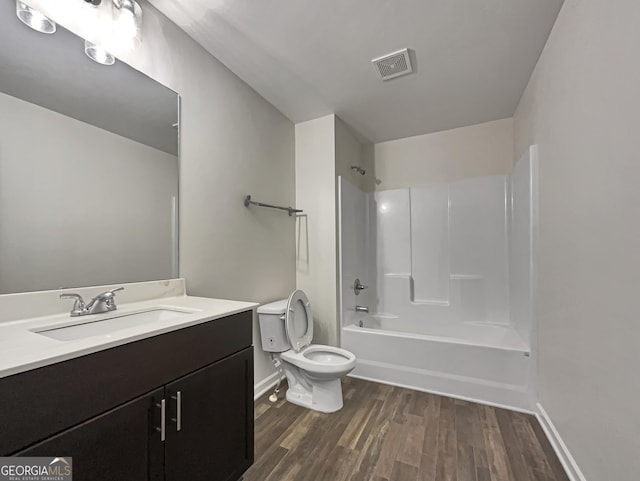 bathroom with visible vents, toilet, wood finished floors,  shower combination, and vanity