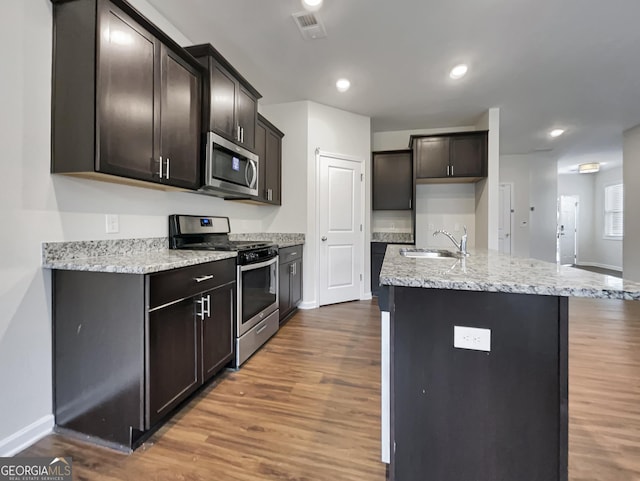 kitchen with stainless steel appliances, wood finished floors, a sink, and visible vents