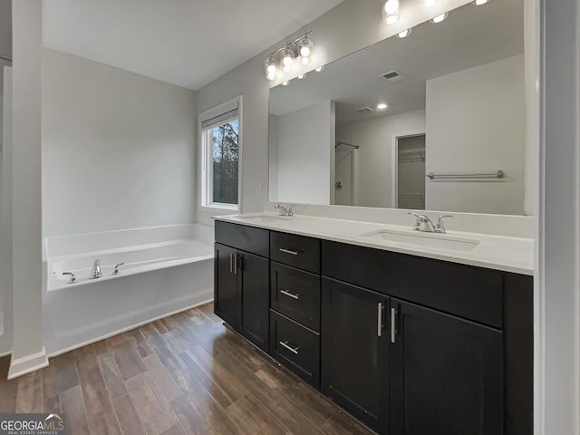 bathroom with visible vents, a sink, a bath, and wood finished floors