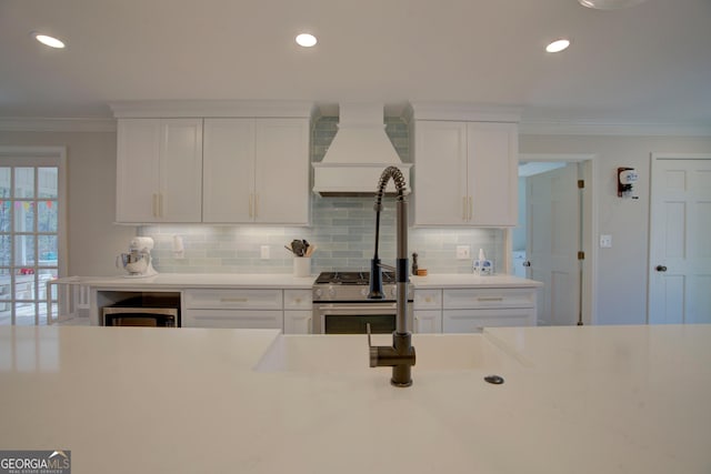 kitchen featuring premium range hood, white cabinets, light countertops, tasteful backsplash, and crown molding