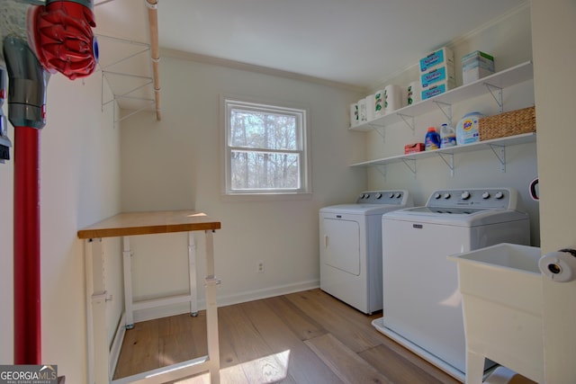 washroom with laundry area, light wood finished floors, baseboards, washer and clothes dryer, and crown molding