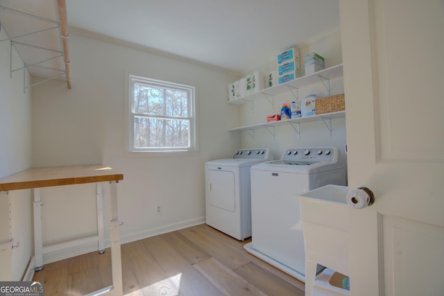 laundry room with laundry area, baseboards, washer and clothes dryer, and light wood finished floors