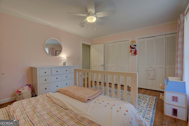 bedroom with ceiling fan, wood finished floors, baseboards, multiple closets, and ornamental molding