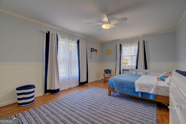 bedroom with a wainscoted wall, crown molding, and wood finished floors