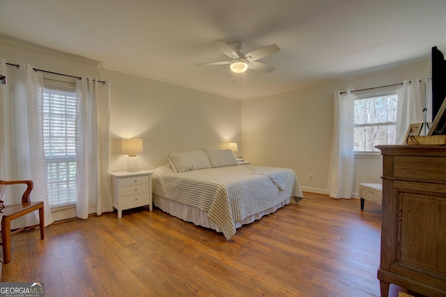 bedroom featuring ornamental molding, a ceiling fan, baseboards, and wood finished floors