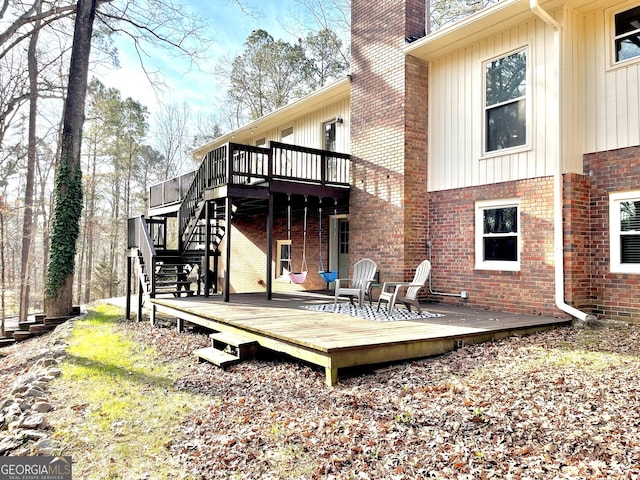 back of house featuring a chimney, stairway, a deck, and brick siding