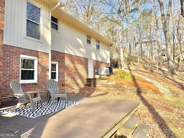 view of property exterior with a deck, cooling unit, and brick siding