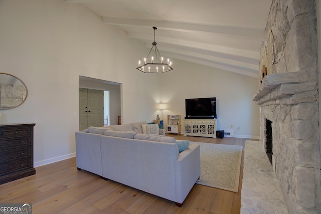 living area with light wood finished floors, a fireplace, beam ceiling, and an inviting chandelier