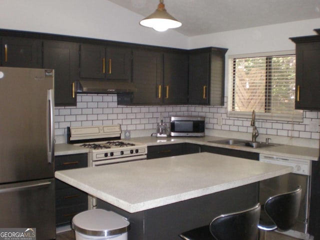 kitchen with light countertops, appliances with stainless steel finishes, a sink, under cabinet range hood, and a kitchen bar