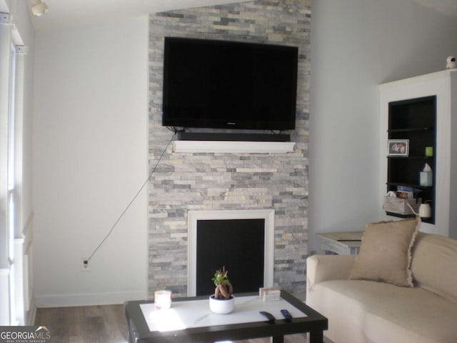 living area featuring a fireplace, baseboards, and wood finished floors